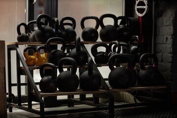 Naklejka na ściany i meble Large display with group of heavy kettlebells of black and yellow color standing on shelves in the corner of modern sports club or gym