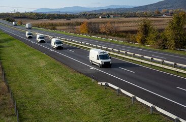 Four White delivery van on the highway. White modern delivery small shipment cargo courier van moving fast on motorway road to city urban suburb. The business distribution and logistics express servic © Bojan