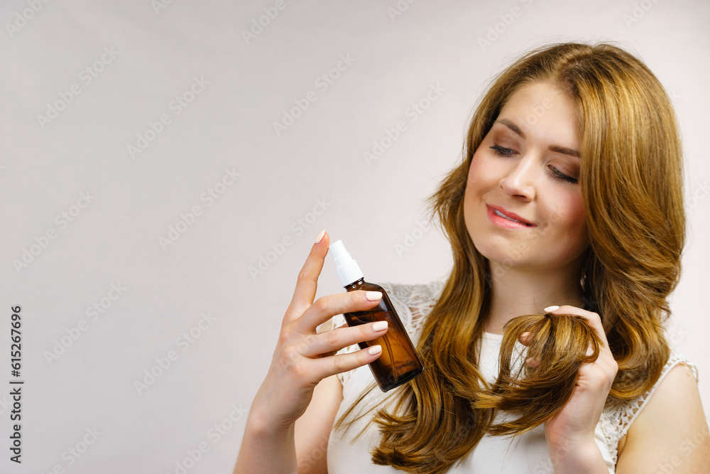 Wall mural Woman applying hair cosmetic