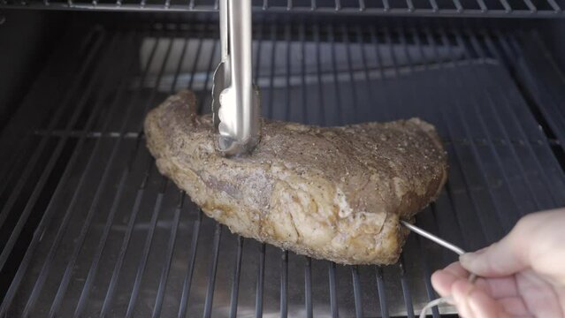 This video shows a temperature probe being placed into brisket steak on a smoker bbq grill.