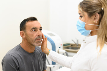 Obraz premium Dermatologist analyzing face of male patient in clinic