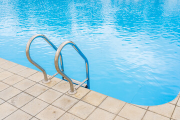 Swimming pool with selective focus on metal stairs and copy space for text.