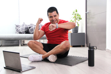 Dark-haired 40-year-old Latino man checks his times while exercising and celebrates his victory for...