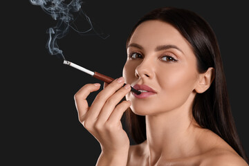 Obraz premium Woman using long cigarette holder for smoking on black background, space for text