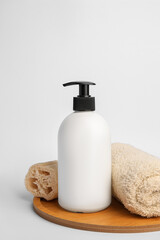Fototapeta na wymiar Bottle with cosmetic product, rolled towel and loofah sponge on white background