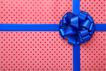 Blue ribbons with bow on red polka dot wrapping paper, top view