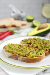 Delicious sandwiches with guacamole and ingredients on white table, closeup