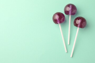 Tasty lollipops on turquoise background, flat lay. Space for text