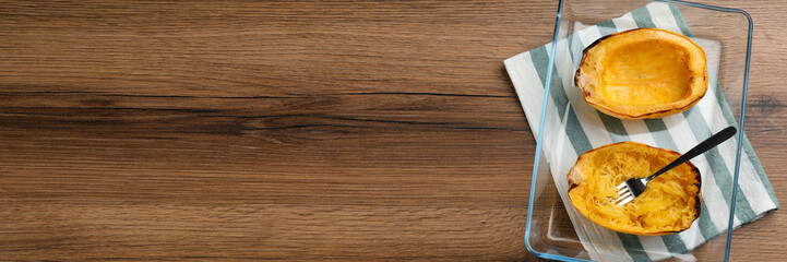 Halves of cooked spaghetti squash in baking dish on wooden table, top view. Banner design with space for text