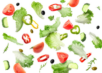 Lettuce leaves, herbs, olives, cut cucumber, bell peppers and tomatoes falling on white background
