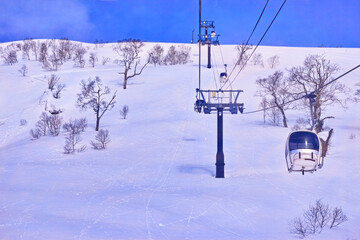 春スキーのニセコスキー場、朝一のゴンドラリフトから見る雪面と青空

