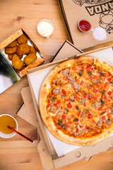 Flat lay of pizza, fried chicken, cup of juice, sauces are on the wooden table. 6 october 2023. Russia