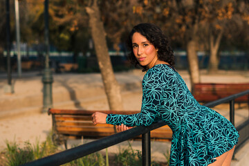 retrato de bella mujer latina posando en un parque estilo 80s 90s con vestido azul, muy alegre y...
