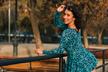 retrato de bella mujer latina con lentes en un parque estilo 80s 90s con vestido azul, muy alegre y...