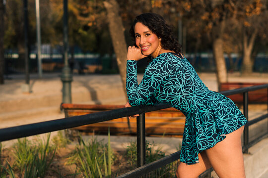 retrato de bella mujer latina posando en un parque estilo 80s 90s con vestido azul, muy alegre y feliz.