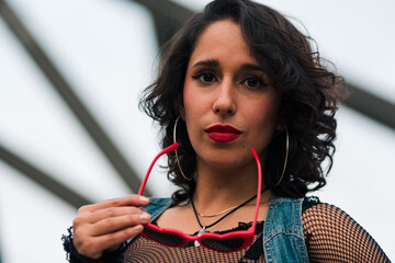 retrato de bella mujer latina mirando de pie con fondo de estructuras metálicas, estilo 80s 90s en...