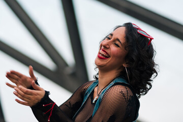 retrato de bella mujer latina con maquillaje sonriendo y riendo con fondo de estructuras metálicas, estilo 80s 90s en un parque al aire libre.