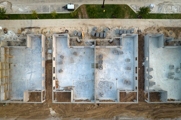 Aerial view of incompleted frame of private home under construction with brick concrete walls ready for installation of wooden roofing beams. Industrial building site