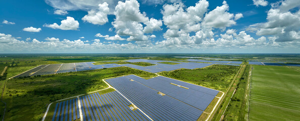 Aerial view of sustainable electric power plant between agricultural farm fields with solar...