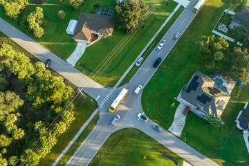 Top view of standard american yellow school bus picking up kids at rural town street stop for their...