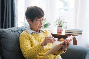 Asian Senior Woman Immersed in the Pleasure of Reading at Home