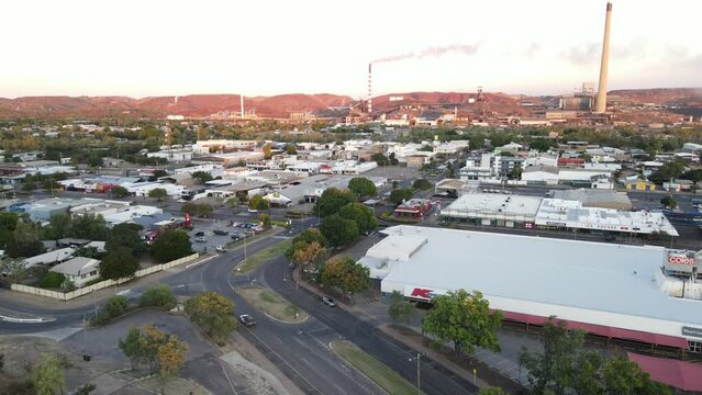Drone aerial of Mount Isa town and mining hub during sunrise over cars driving on road