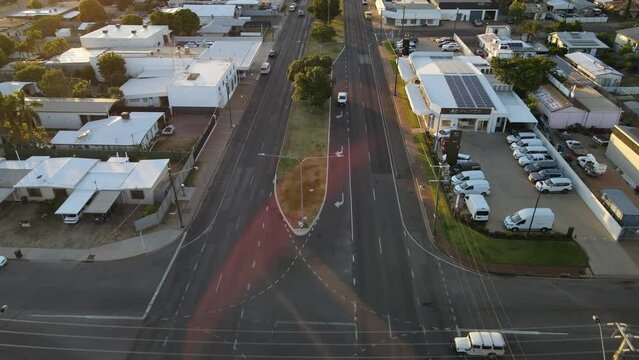 Drone aerial of Mount Isa moving backwards panning up to show sun flare over road with cars driving