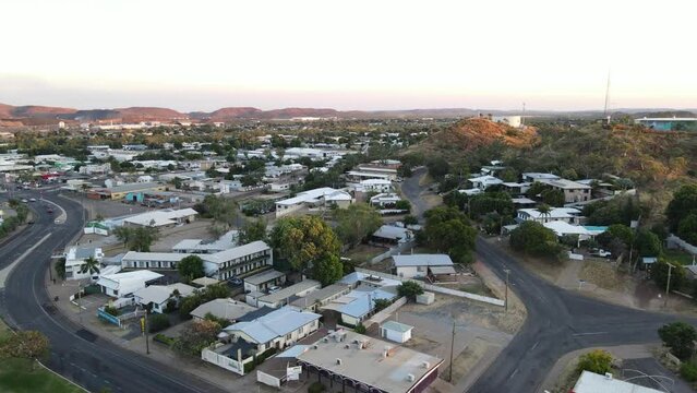 Drone aerial of Mount Isa town moving forward down during sunrise showing mountains