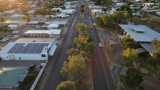Drone aerial of Mount Isa town moving forward with a slow pan down during sunrise over a road