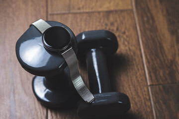 Connected Fitness: Smartwatch and Dumbbells on Wooden Floor.