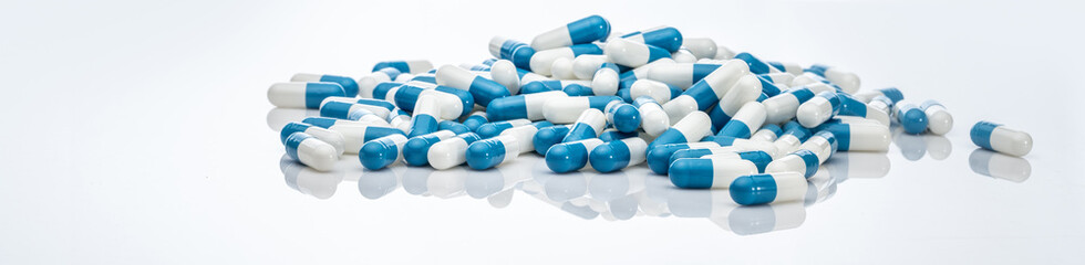 Blue-white antibiotic capsule pills on white background. Pile of antibiotic drug. Antibiotic drug...