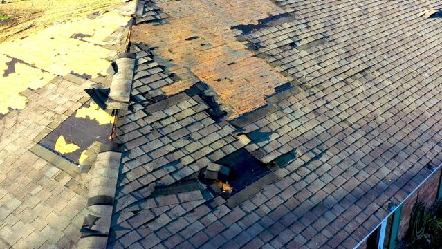 Tornado damage to roof with missing shingles, in need of repair