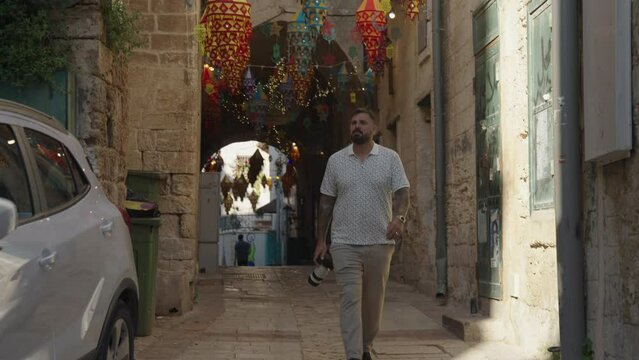 Man with camera walks into sunlight from old town alley in Nazareth