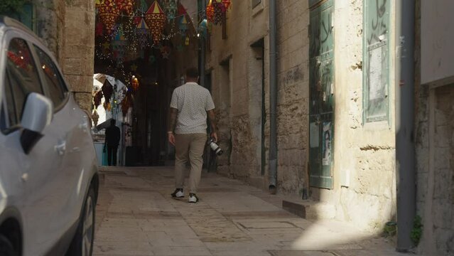 Male photographer walks in narrow covered alley in old town, Nazareth