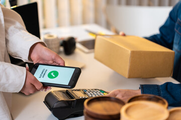 Close up hands of customer using mobile phone paying for goods package. 