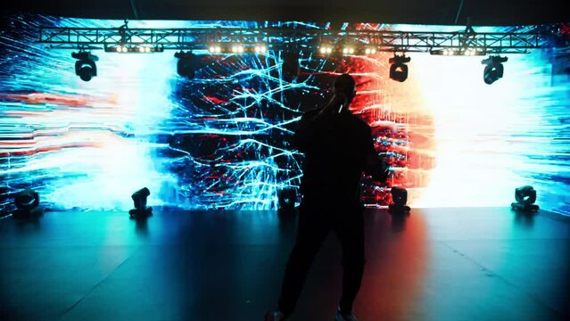African-American Black rap artist performing his gig in front of a concert crowd on a stage of a large venue, surrounded by bright flashig lights
