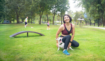 sporty asian woman playing with puppy to training dog leash at park with happy moment