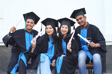 Group of graduated students sitting and celebrate their diploma and academic degree on graduation day