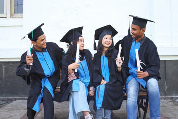 Group of graduated students sitting and chit chat with happines after celebrate their diploma degree on graduation day