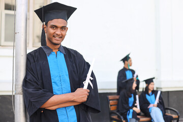 Portrait of Asian bachelor man smiling at camera and showing okay sign near blurred friends in...