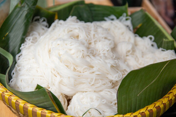a pannier full of white rice noodle wrap in banana leaf for sale