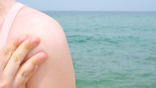 Smear of sunscreen on female shoulder against the backdrop of the sea.