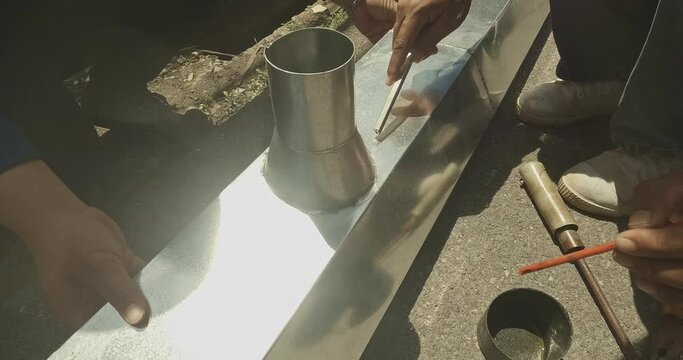 Zinc rain gutter welding by using soldering copper. Technician is welding aluminum pipe by using soldering copper.