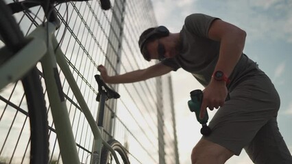 Cyclist athlete massages body with percussion therapy gun to relieve post workout muscle aches and pains on cycling workout. Massage percussion device after workout. Warming up muscles with massager