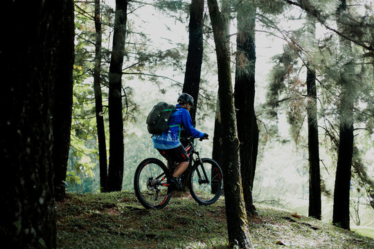 An asian man in a blue shirt and wearing a helmet is very excited to do his cycling activity during his off time on a sunny morning - Powered by Adobe