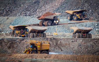 Six trucks in a busy modern gold mine in Western Australia. One water truck and five large haul...