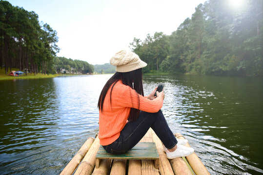A woman wearing an orange shirt rides a bamboo boat. At Pang Ung Reservoir, Mae Hong Son, Thailand