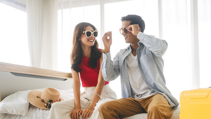Young adult southeast asian couple traveler wear sunglasses at home in bedroom on day
