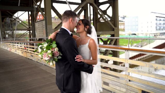 Beautiful young newlyweds posing for pictures on a bridge after the wedding 02