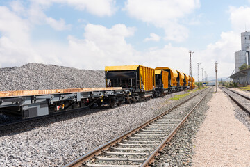 Obraz premium Freight train wagons with pebbles - Trains with special platforms for transporting railway rails